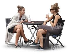 two women sitting at a table talking to each other while one holds a cup in her hand