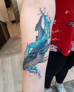 a woman's arm with a whale tattoo on it