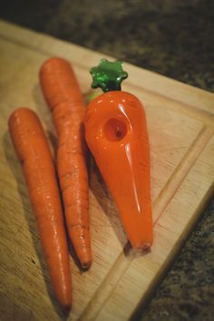 three carrots are sitting on a cutting board