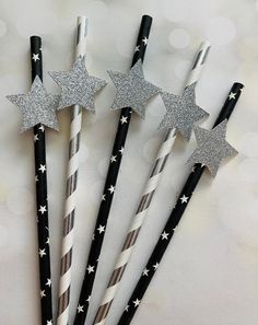 four black and white straws with silver stars on them