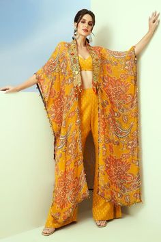 Yellow organza longline kaftan with sequins hand embroidered borders and floral and paisley print. Comes with dobby georgette bell-bottom pant and a padded bustier.
Components: 3
Pattern: Printed, Hand embroidered
Type Of Work: Floral, Paisley, Sequins
Neckline: Sweetheart
Sleeve Type: Kaftan: Flared Sleeves, Bustier: Sleeveless
Fabric: Dobby georgette, Kaftan: Organza
Color: Yellow
Other Details: 
Tasseled detailing on kaftan
Occasion: Sangeet - Aza Fashions Kaftan And Pants, Organza Kaftan, Kaftan For Women, Printed Organza, Long Kaftan, Sharara Set, Fashion Design Sketches, Bell Bottom Pants, Yellow Print