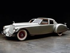 an old silver car parked in a garage