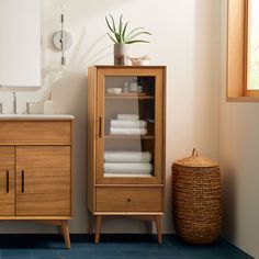 a bathroom with a cabinet, sink and toilet paper roll on the floor next to it