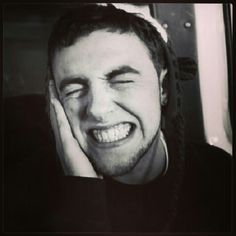 black and white photo of a man laughing on a bus with his hand to his face