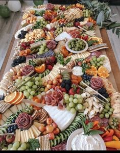 a long table filled with lots of different types of cheeses and fruits on it