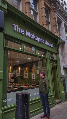 a man standing in front of the mokapot house on a city street corner