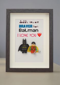 a shadow frame with two legos in it that says daddy you are braver than batman i love you