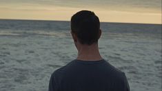 a man standing in front of the ocean looking out to sea