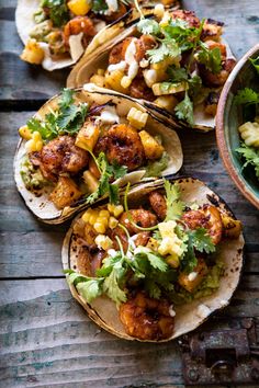 three tacos with guacamole, corn and salsa on a wooden board