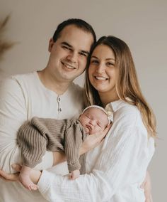 a man and woman holding a baby in their arms