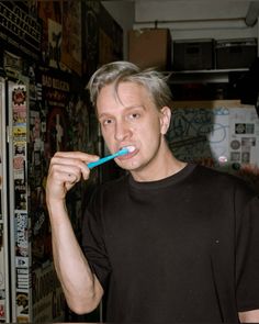 a man brushing his teeth in front of a refrigerator