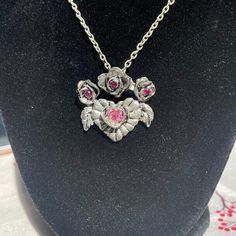 Vintage thrifted pendant necklace with a winged heart, roses, and set with pink stones. Dark silver-toned, marked on back as "CCI©". I have plenty more jewelry listed in my shop, new and old! If you have time, take a look! We have been selling online but are new to Etsy! We sell new & old, useful and odd, and everything in between. We keep our prices low and our descriptions fair and accurate. We aren't a storefront or mega-corporation. We love finding and selling items that people can enjoy and Valentine's Day Silver Jeweled Necklaces, Silver Jeweled Necklaces For Valentine's Day, Valentine's Day Silver Jewel Necklace, Silver Rose Design Necklace, Silver Rose Design Metal Necklace, Heart-shaped Rose Design Necklace For Valentine's Day, Silver Metal Necklace With Rose Design, Gothic Rose-colored Jewelry For Gifts, Rose-colored Gothic Jewelry For Gift