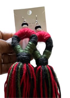 a pair of earrings with red, green and black yarn