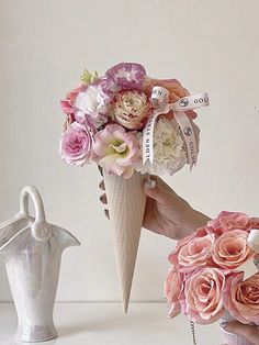 a hand holding a bouquet of flowers and an ice cream cone