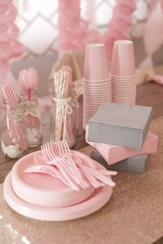 a table with pink plates, napkins and other items on top of the table