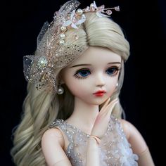 a doll with long blonde hair wearing a tiara and pearls on it's head