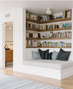 a living room filled with furniture and lots of books on the shelf above it's couch