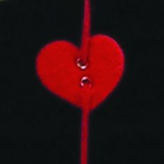 a red heart shaped object with water drops on it's side and a black background