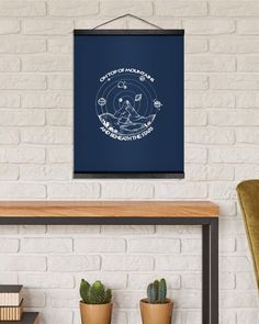 a red poster hanging on the wall above a table with two potted cacti