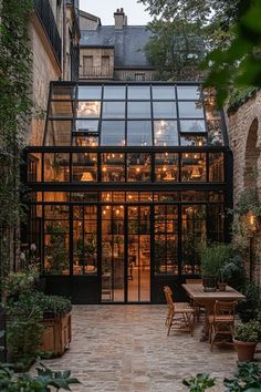 an outdoor dining area in the middle of a courtyard with tables and chairs, surrounded by greenery