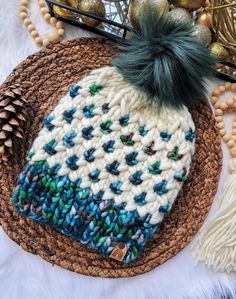 a white and blue knitted hat sitting on top of a woven mat next to christmas decorations