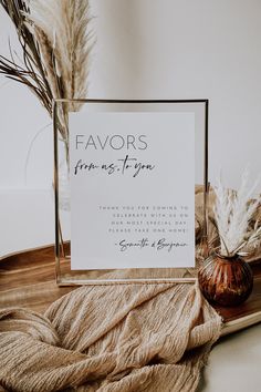 a photo frame sitting on top of a table next to some dried plants and a vase