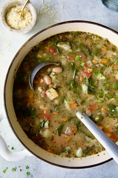 a bowl of soup with a spoon in it next to rice and other food items