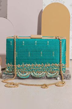 "Introducing Tari, a collection of exquisite raw silk potlis and clutches. Comes in an array of vibrant colors including regal purple, pink, mehndi green, warm mustard, and turquoise. The potli and the clutches are adorned with a delicate handcrafted embroidered border. The richness of material, captivating colors, and intricate details are an homage to South India. Perfect for all occasions, weddings, functions, and festive celebrations. Color: Turquoise Embroidered front and back. Dimensions (LxB): 7.75\"x4.5\" (19.7 cm X 11.4 cm) Handle length: 47\" (120 cm) Handle drop: 23\" (58 cm) Material: Embroidered pure silk, tissue inner lining, gold embroidered border lace, poly satin lining, gold metal clutch frame, gold metal sling. Features: metal lock closure, detachable metal sling." Elegant Embroidered Fabric With Gota Work For Festive, Elegant Party Embroidered Art Silk Fabric, Elegant Embroidered Fabric With Gota Work For Diwali, Elegant Diwali Embroidered Fabric With Gota Work, Elegant Green Embroidered Dola Silk Fabric, Elegant Embroidered Fabric For Navratri Party, Elegant Green Dola Silk Embroidered Fabric, Elegant Art Silk Fabric With Zari Embroidery, Evening Embroidered Fabric With Zari Work