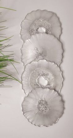 three pieces of art glass sitting on top of a table next to grass and flowers