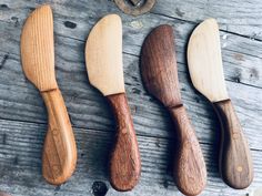 four wooden spoons are lined up on a table