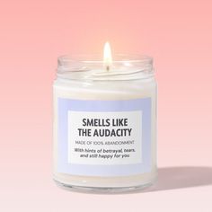 a candle that says smells like the audacy on it with a pink background