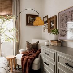 a living room with white furniture and pictures hanging on the wall, along with a lamp