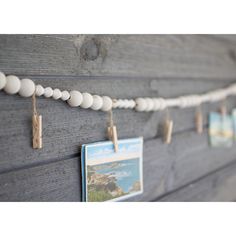 a wooden board with clothes pins and pictures hanging from it's pegs on the wall