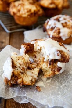 cinnamon roll muffins with white icing on top sitting on a piece of parchment paper