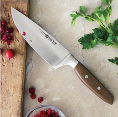 a knife and bowl of cranberries on a cutting board