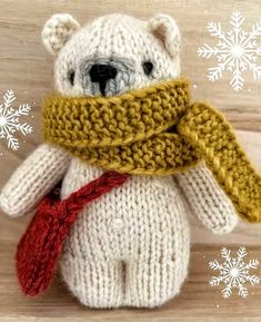 a knitted teddy bear with a scarf around it's neck on a wooden surface