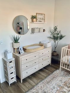 a baby's room with a crib, dresser and mirror on the wall