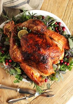 a roasted turkey on a platter with fresh herbs and cranberry garnish