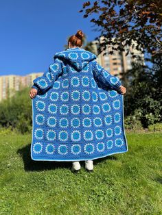 a woman is standing in the grass with a blue blanket on her back, and she has