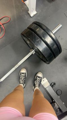 a person standing in front of a barbell with their feet on the ground next to it