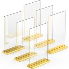 four gold and clear acrylic frames on a white background with no one in the photo