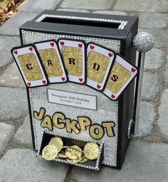 a card box that is sitting on the ground with some gold coins in front of it