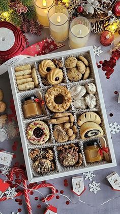 a box filled with lots of different types of cookies next to candles and christmas decorations