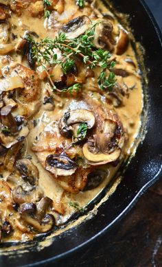 a skillet filled with mushrooms and gravy on top of a wooden table