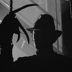 black and white photograph of a man with a hat on holding a knife in his hand