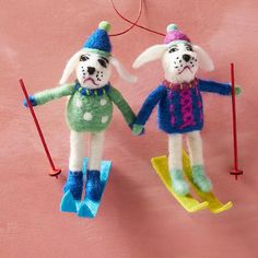 two stuffed animals hanging from strings on a pink wall