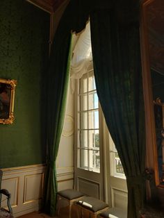 an ornate room with green walls and drapes on the windowsill, along with a bench