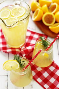 two glasses filled with lemonade sitting on top of a red and white checkered table cloth