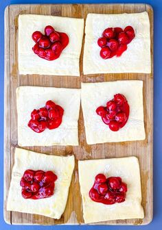 four squares of dough with cherries on them