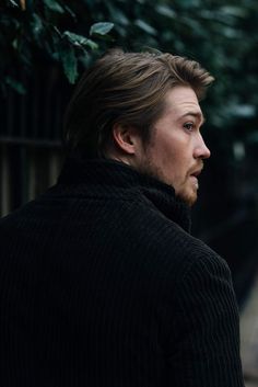 a man standing next to a tree looking off into the distance